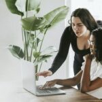 woman helping another woman with a computer