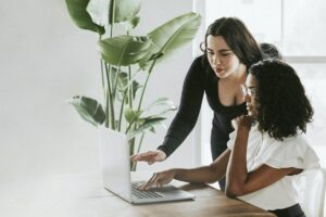 woman helping another woman with a computer