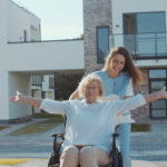 Happy woman in a wheelchair being pushed by a happy care worker
