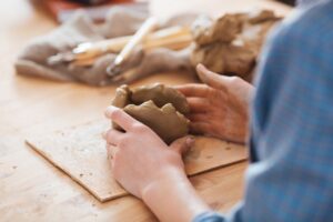 person sculpting clay on a wooden table