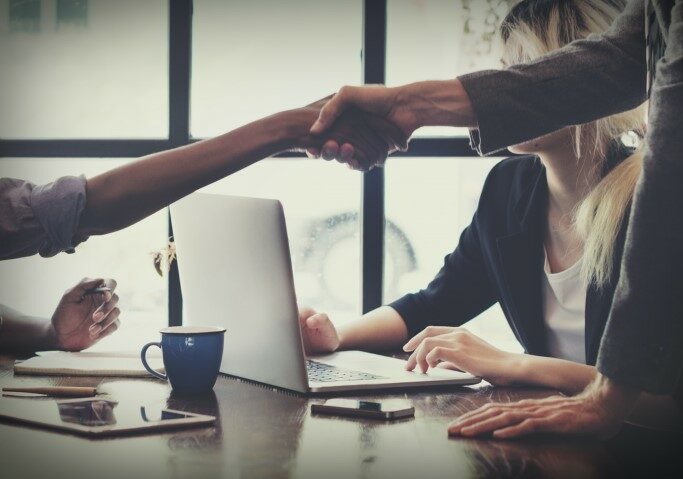 Agreement, hands reaching across desk